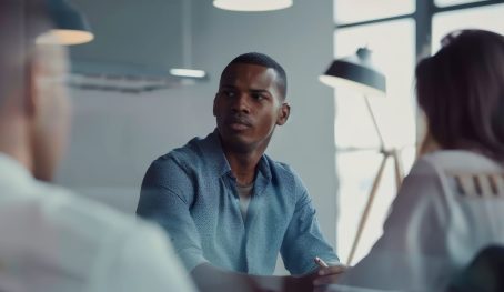 A man attentively participating in a meeting in a bright, minimalistic office, indicating collaboration and a professional work atmosphere