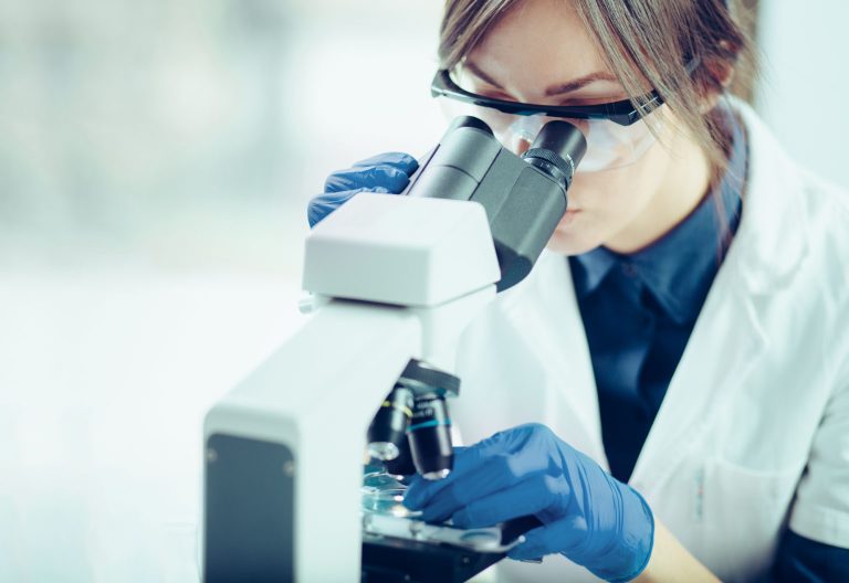 Young scientist looking through a microscope in a laboratory in a clinical-development setting